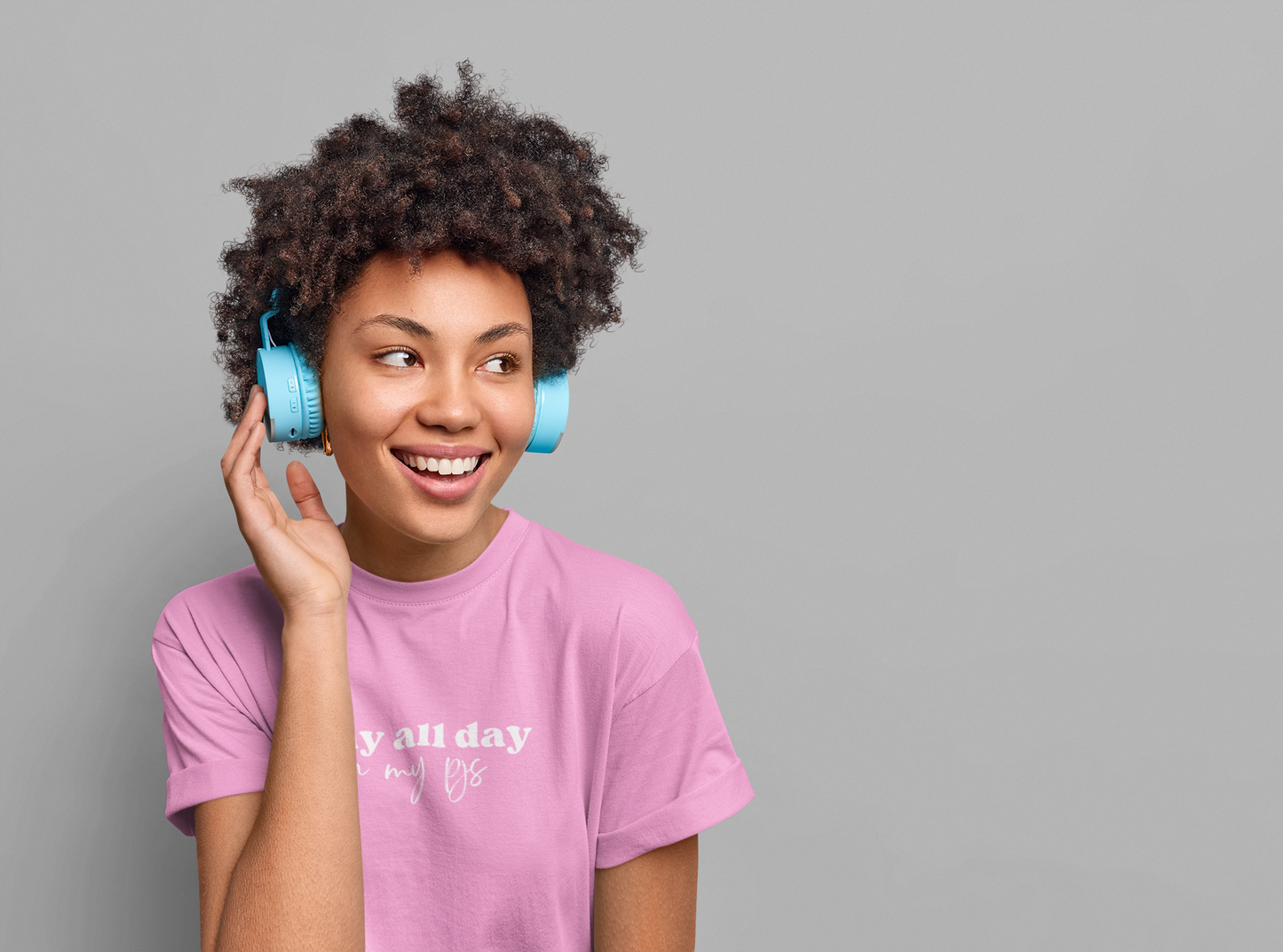 A woman wearing a Slay All Day in my PJs Tee from Sharp Tact Kreativ | Tees & Gifts with Encouraging Messages to Brighten Your Day with a Bit of Wit, with headphones.