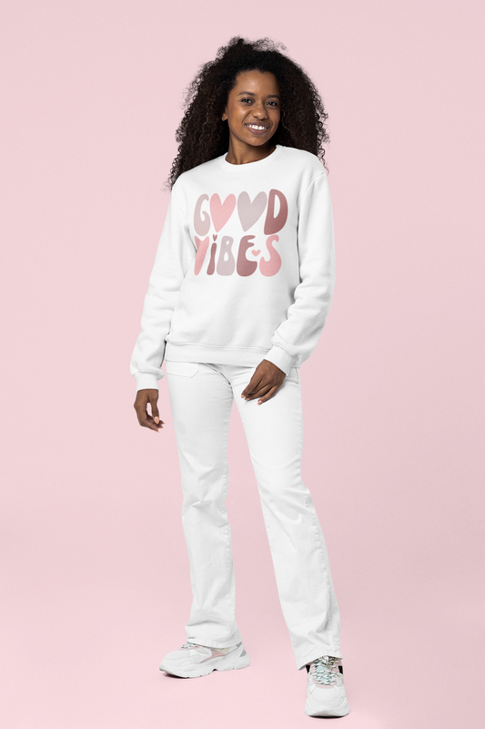 A woman wearing a white Sharp Tact Kreativ "Good Vibes" sweatshirt.