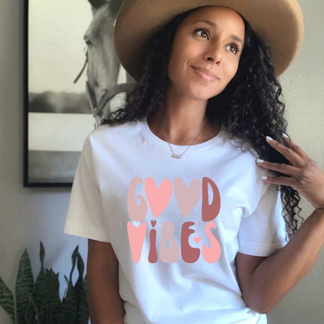 A woman wearing a hat and t - shirt that says good vibes by Sharp Tact Kreativ
