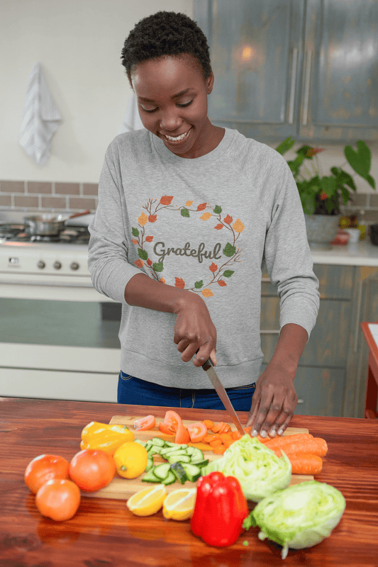 African-American-woman-smiling-and-cutting-up-vegetables-wearing-Grateful-sweatshirt-by-Sharp-Tact-Kreativ