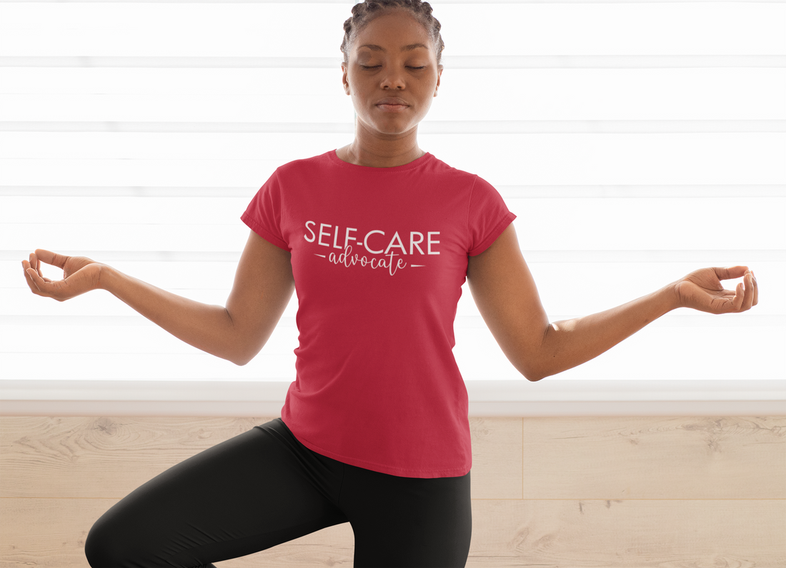 A woman doing yoga in a red t - shirt by Sharp Tact Kreativ that says self care advocate 