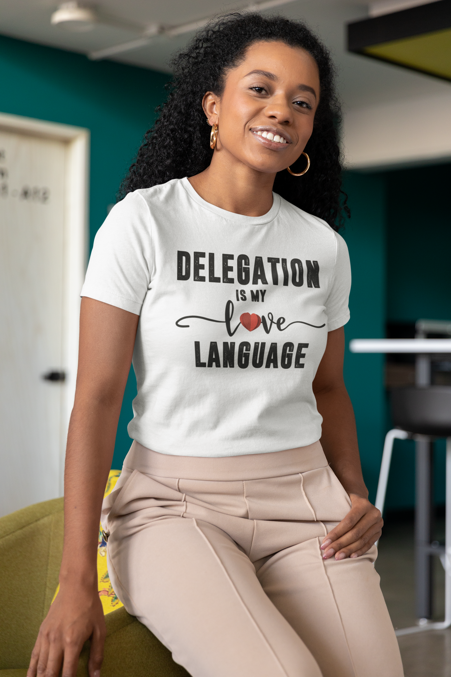 A woman wearing a white t-shirt that says Sharp Tact Kreativ | Tees & Gifts with Encouraging Messages to Brighten Your Day with a Bit of Wit - Delegation is My Love Language Tee.
