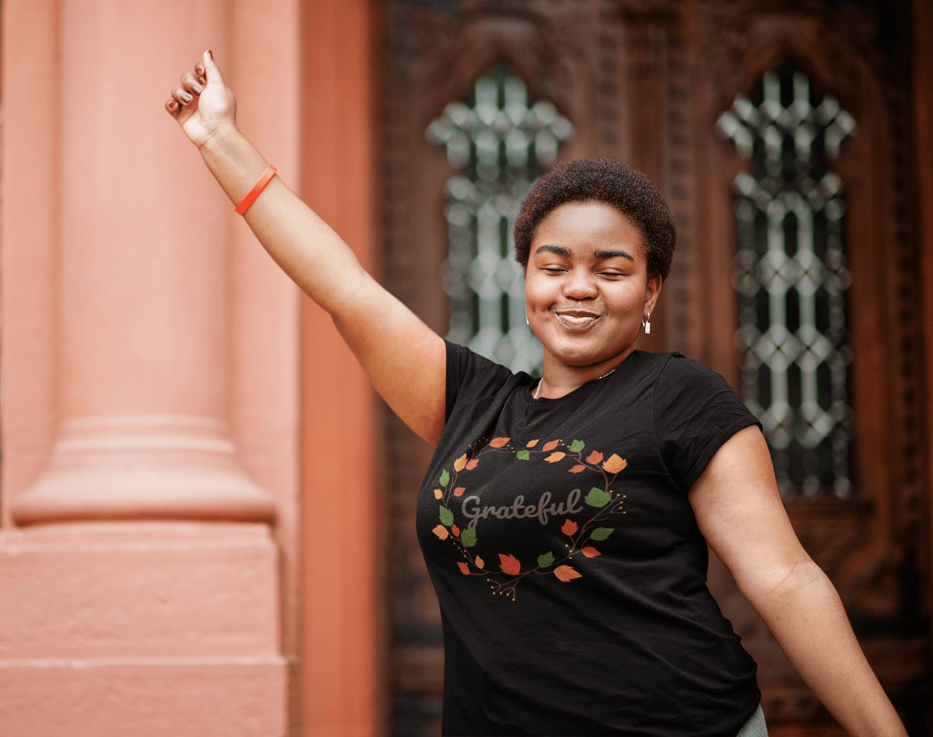 A woman in a comfortable Grateful Tee by Sharp Tact Kreativ, with her arm raised, serving as a reminder.