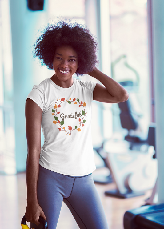 A woman in a gym wearing a Sharp Tact Kreativ Grateful Tee, serving as a reminder to appreciate every moment.