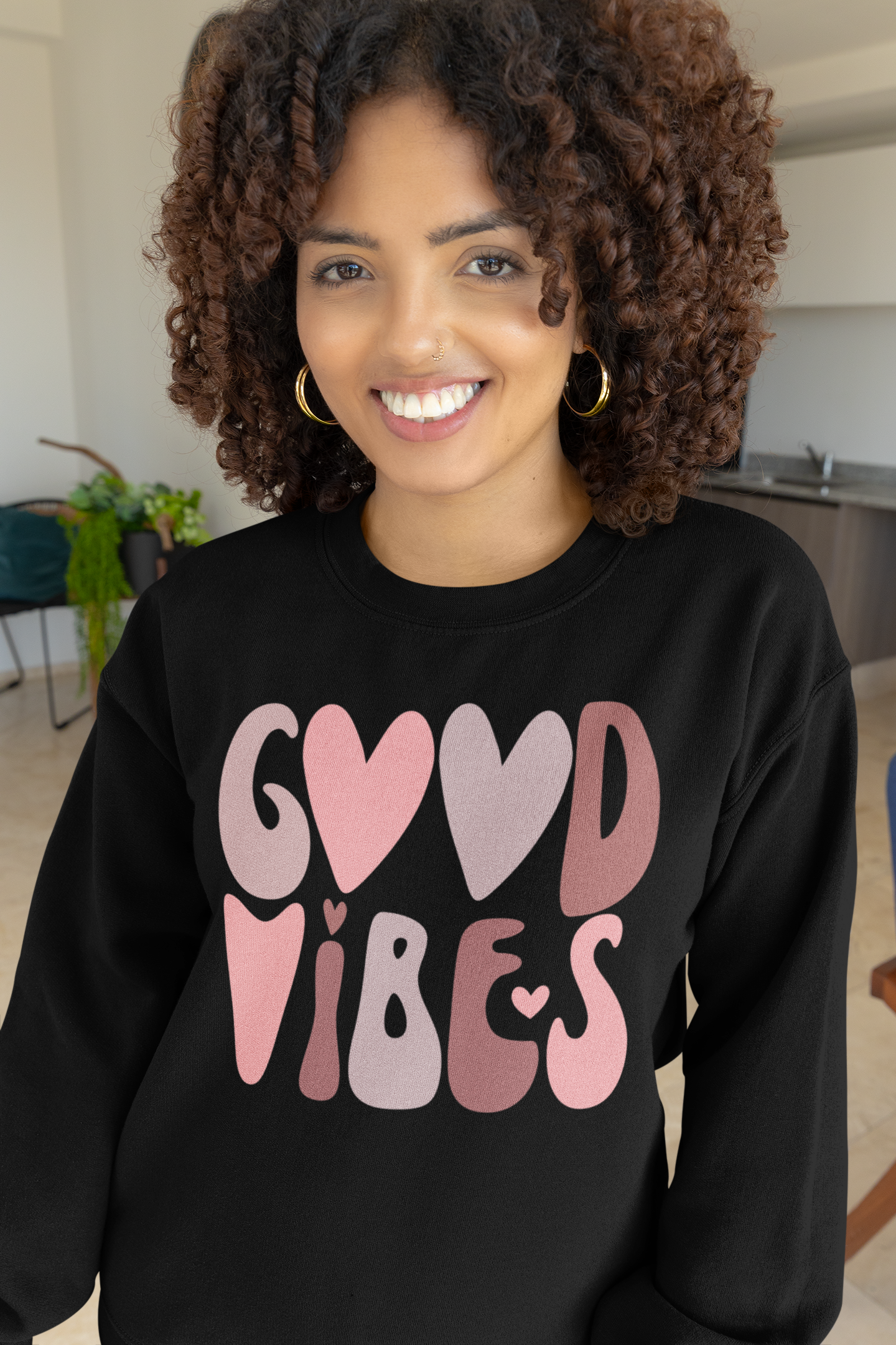 A woman wearing a black Good Vibes Sweatshirt by Sharp Tact Kreativ. The sweatshirt is made of cotton and polyester and comes with a sizing chart.