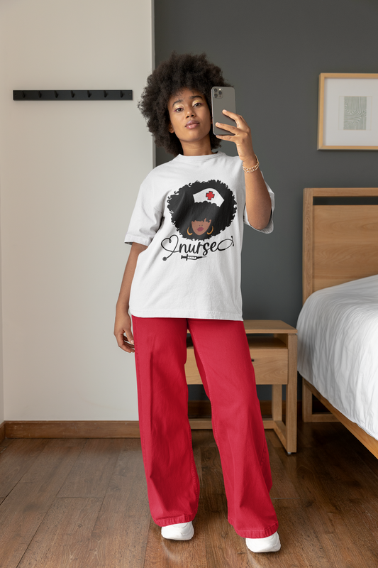 A woman wearing red pants and a Nurse (Curly) Tee from Sharp Tact Kreativ | Tees & Gifts with Encouraging Messages to Brighten Your Day with a Bit of Wit brand, taking a selfie.