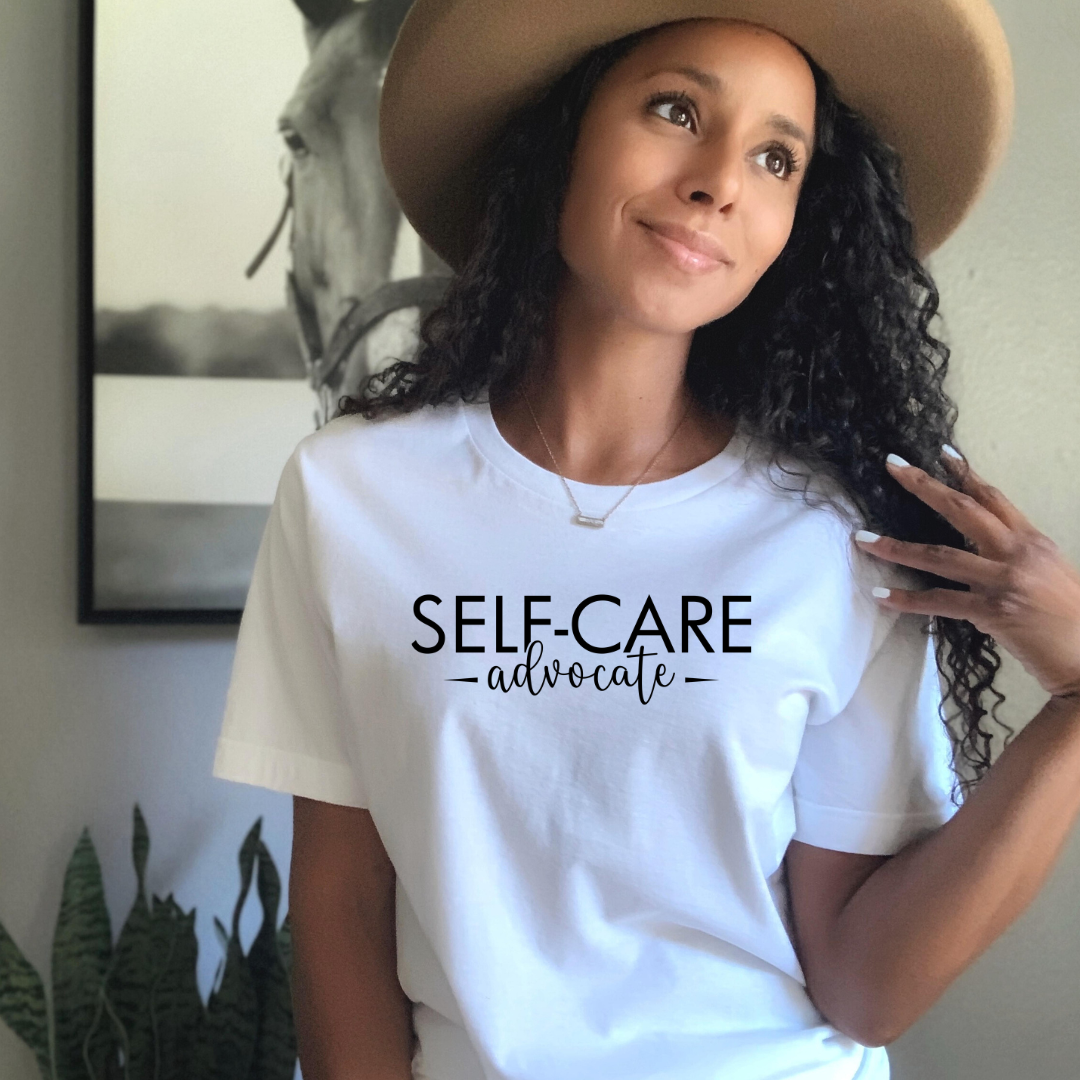 A woman wearing a white Self-Care Advocate Tee by Sharp Tact Kreativ | Tees & Gifts with Encouraging Messages to Brighten Your Day with a Bit of Wit.